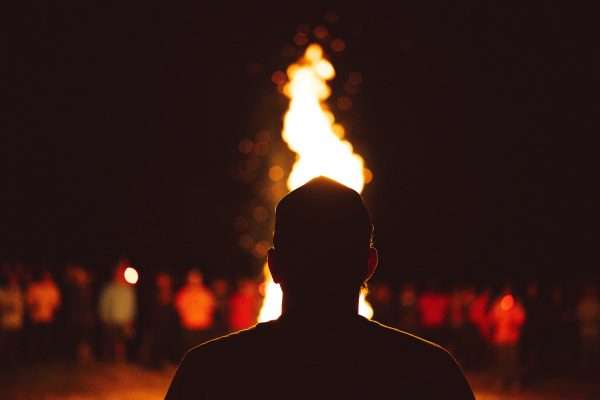 Tall Flame of a Bonfire Illuminating a Group of People